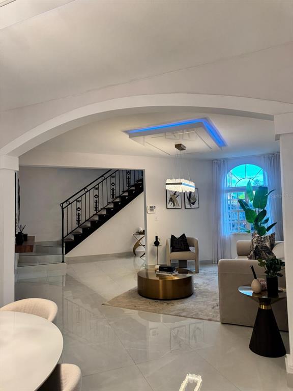 A living room features a modern chandelier, blue tray ceiling lighting, and a staircase — B7 BRIGHTON COUNTRY CLUB, DORADO, PR