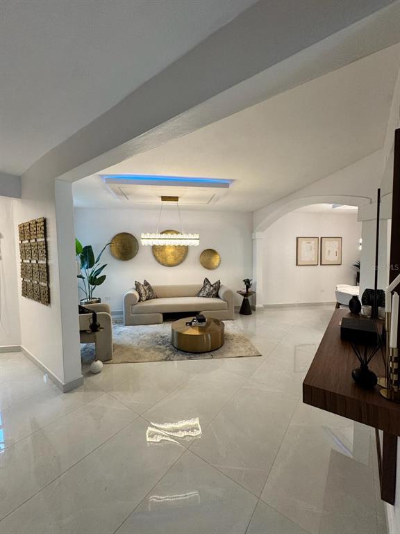 A modern living room features a beige sofa, gold wall art, and polished tile flooring — B7 BRIGHTON COUNTRY CLUB, DORADO, PR