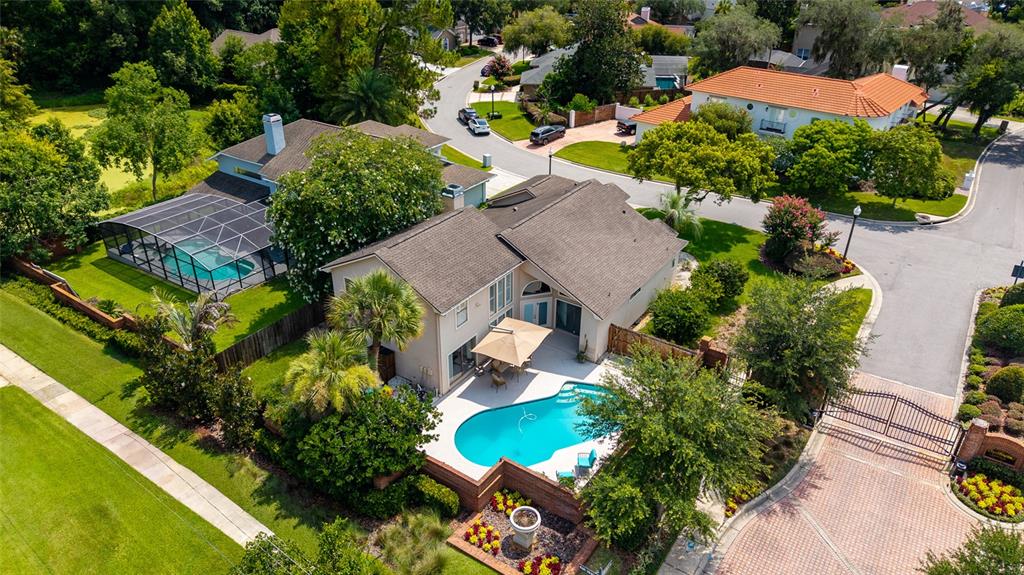 An aerial view shows a two-story house with two swimming pools and a gated driveway — 933 BEARDED OAKS TERRACE, LONGWOOD, FL