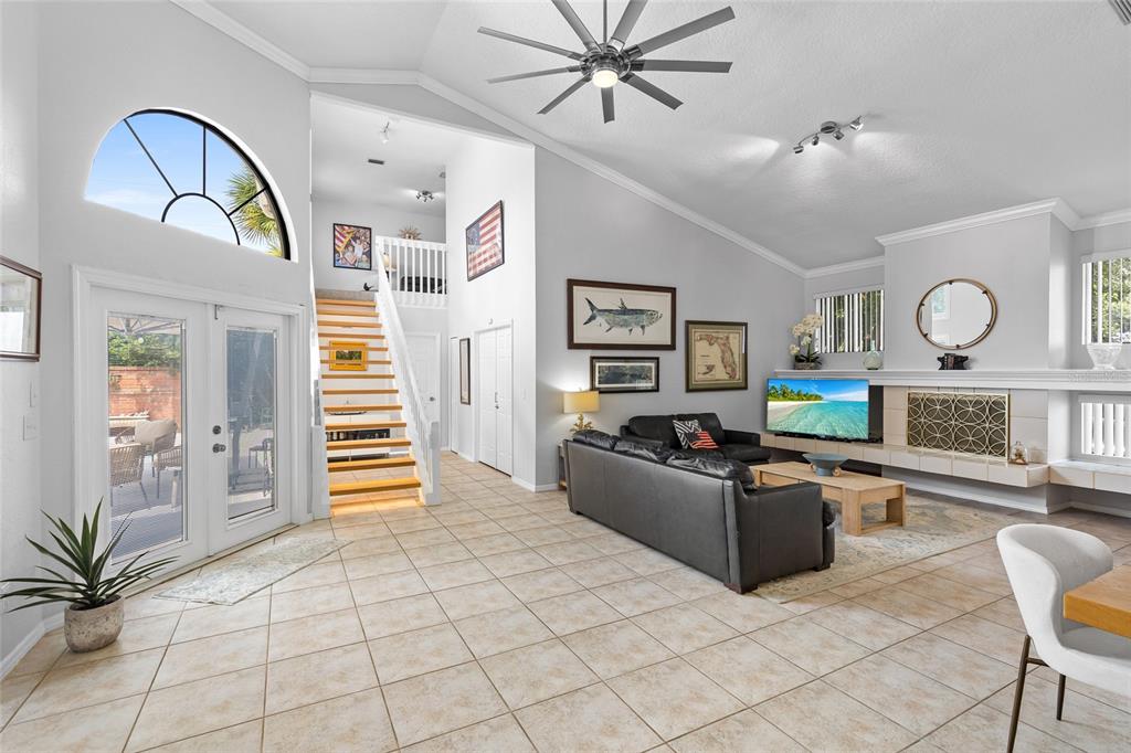 A living room with tile floors, a vaulted ceiling, a staircase, and a fireplace — 933 BEARDED OAKS TERRACE, LONGWOOD, FL