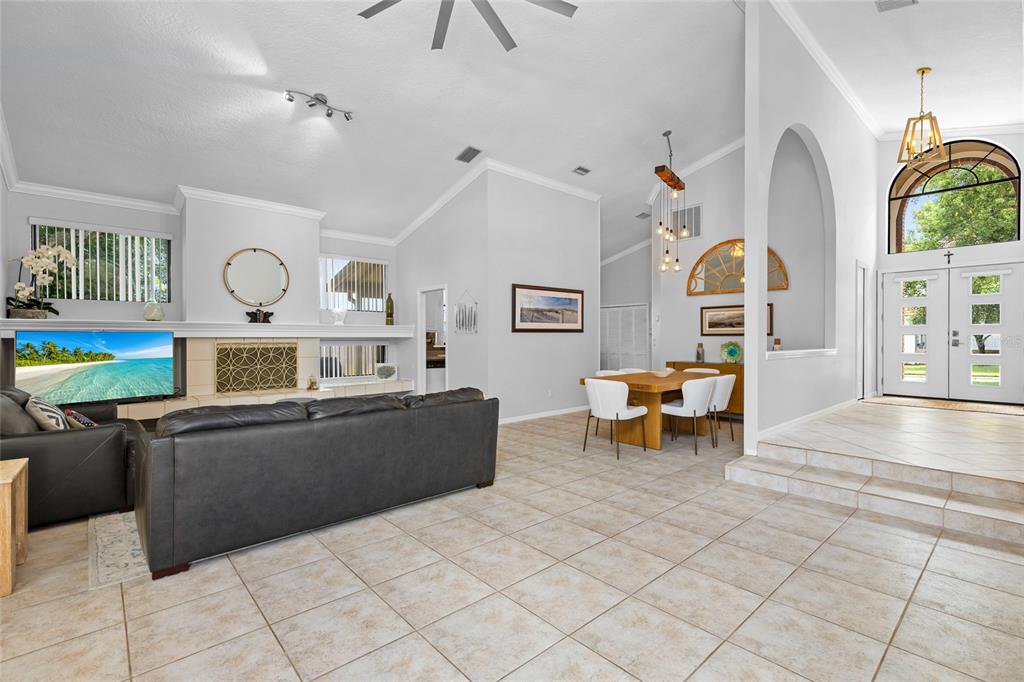 A living room and dining area with tile floors, a fireplace, and a double-door entrance — 933 BEARDED OAKS TERRACE, LONGWOOD, FL