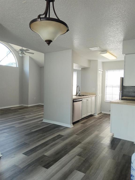 A kitchen with white cabinets and gray wood-look flooring opens into a living area — 2931 RIO GRANDE TRL UNIT D, KISSIMMEE, FL
