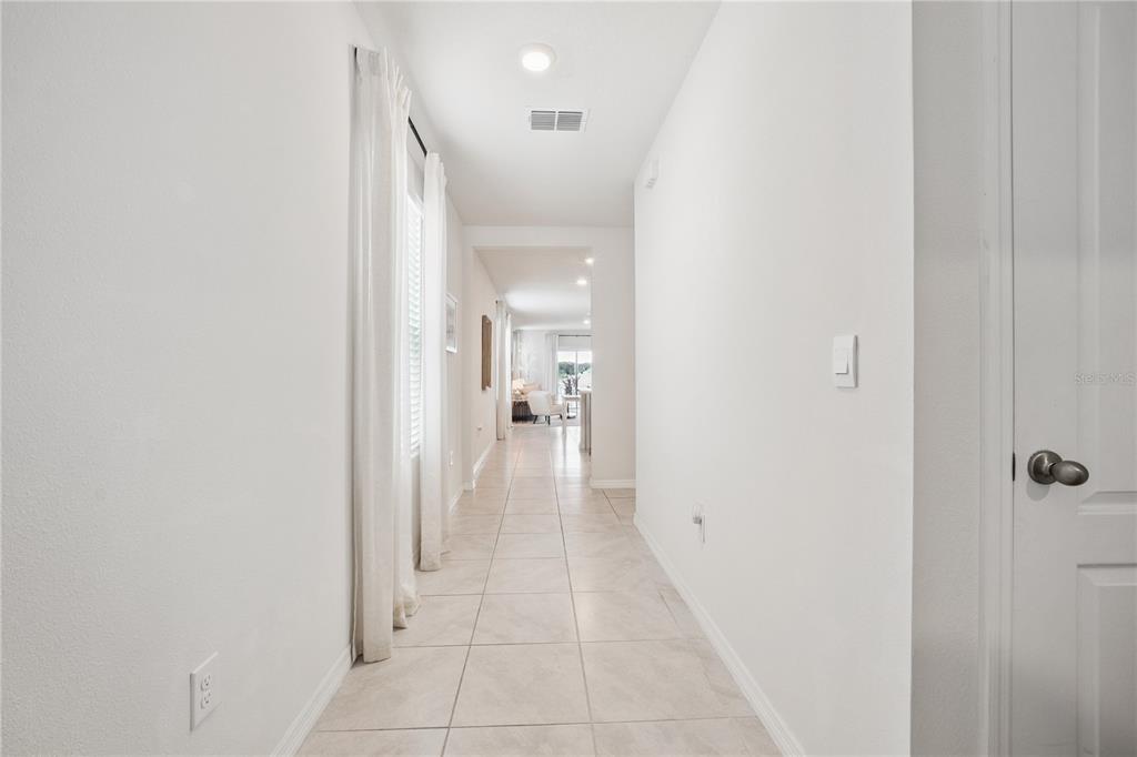 A bright hallway features light-colored tile flooring, white walls, and a view toward a living area — 2698 ROWAN STREET, TAVARES, FL