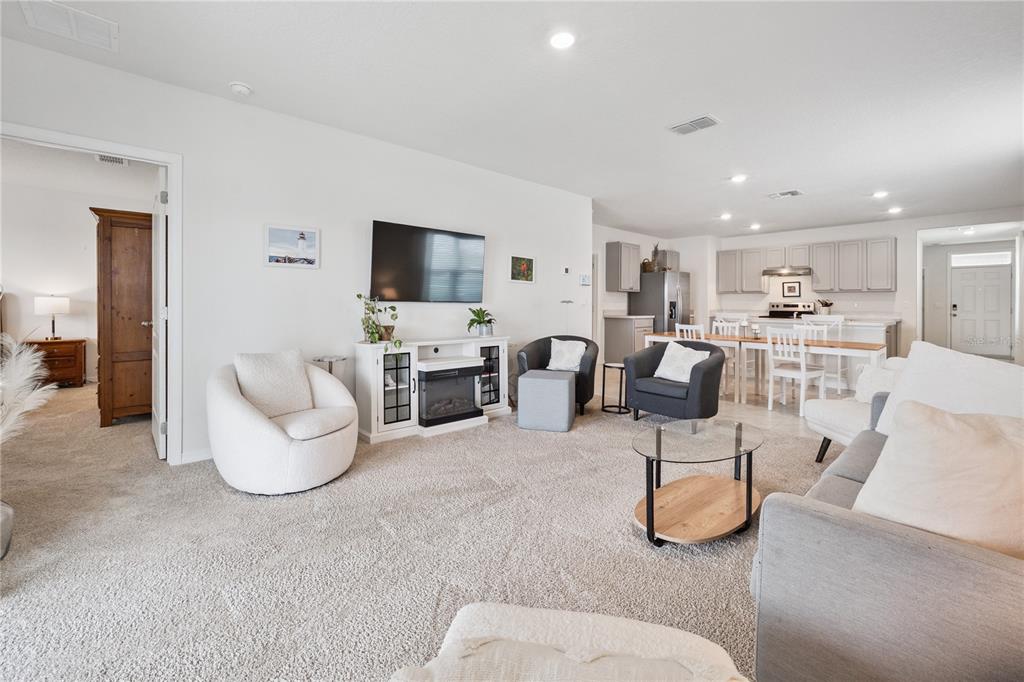 A living room with carpeted floors, a fireplace console, and an open kitchen area — 2698 ROWAN STREET, TAVARES, FL