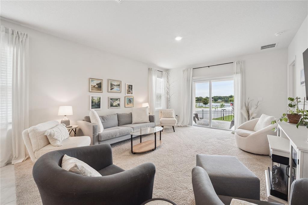 A bright living room features a gray sofa, accent chairs, and a sliding glass door — 2698 ROWAN STREET, TAVARES, FL