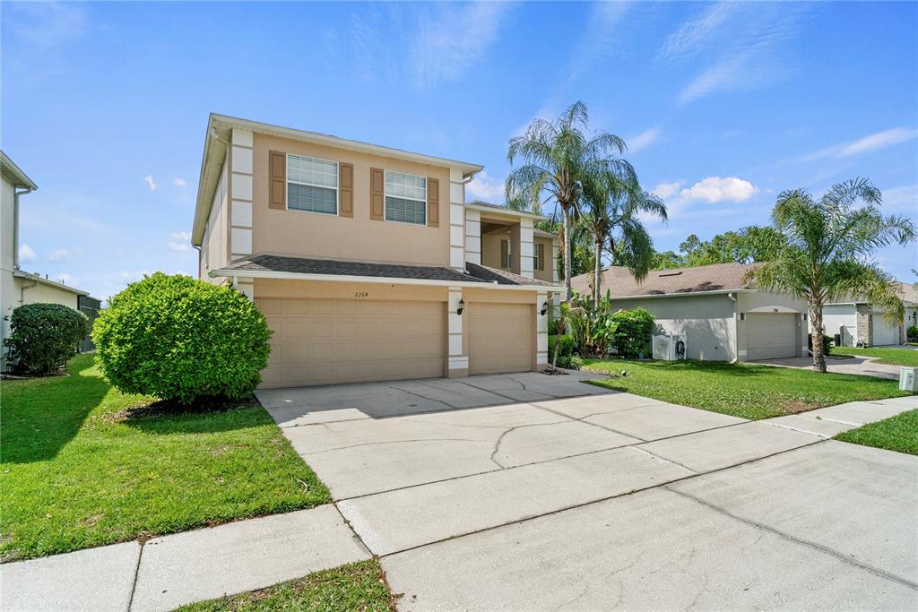 A two-story suburban house with a tan exterior, a three-car garage, and a concrete driveway — 2264 STONE CROSS CIRCLE, ORLANDO, FL