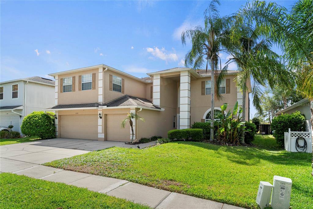 A two-story suburban house with a tan stucco exterior, a two-car garage, and palm trees — 2264 STONE CROSS CIRCLE, ORLANDO, FL