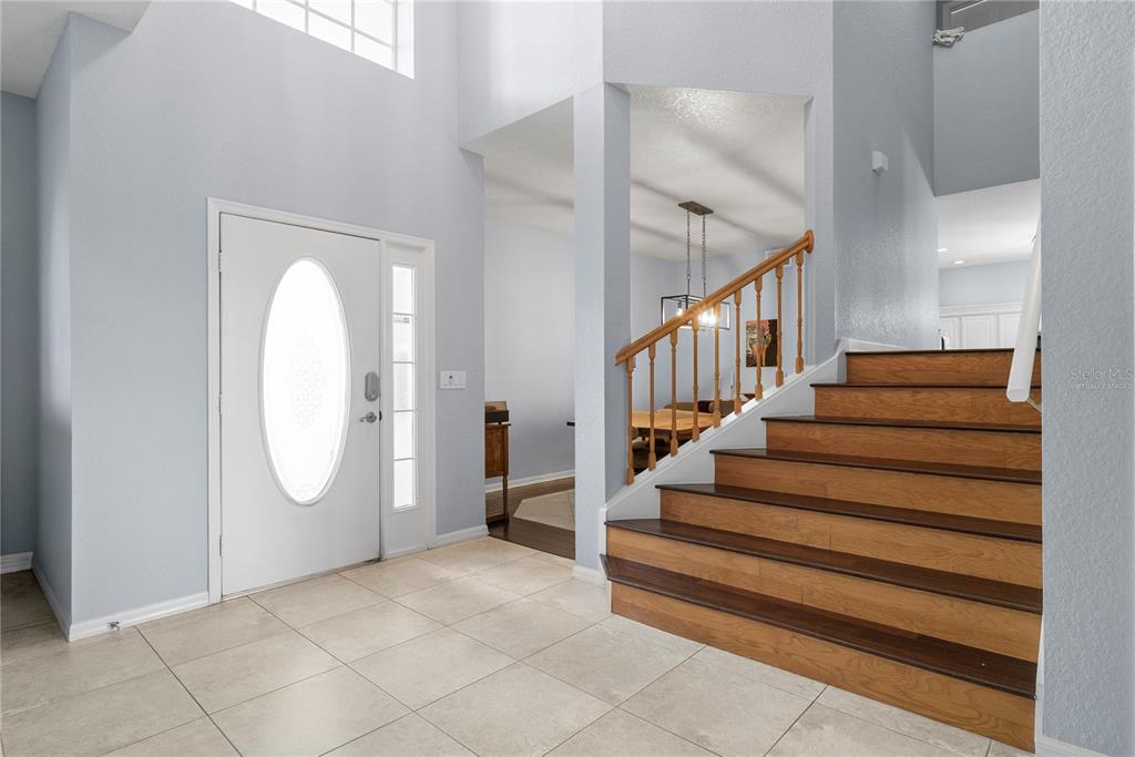 An entryway features a white front door, tiled floors, and a wooden staircase with railings — 2264 STONE CROSS CIRCLE, ORLANDO, FL