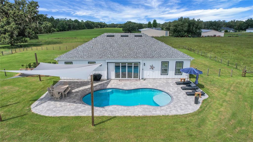 An aerial view of a white house with a pool, patio, and shade sail — 10757 COUNTY ROAD 223, OXFORD, FL