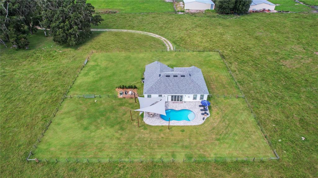 A white single-story house with a dark roof sits on a large, grassy lot — 10757 COUNTY ROAD 223, OXFORD, FL