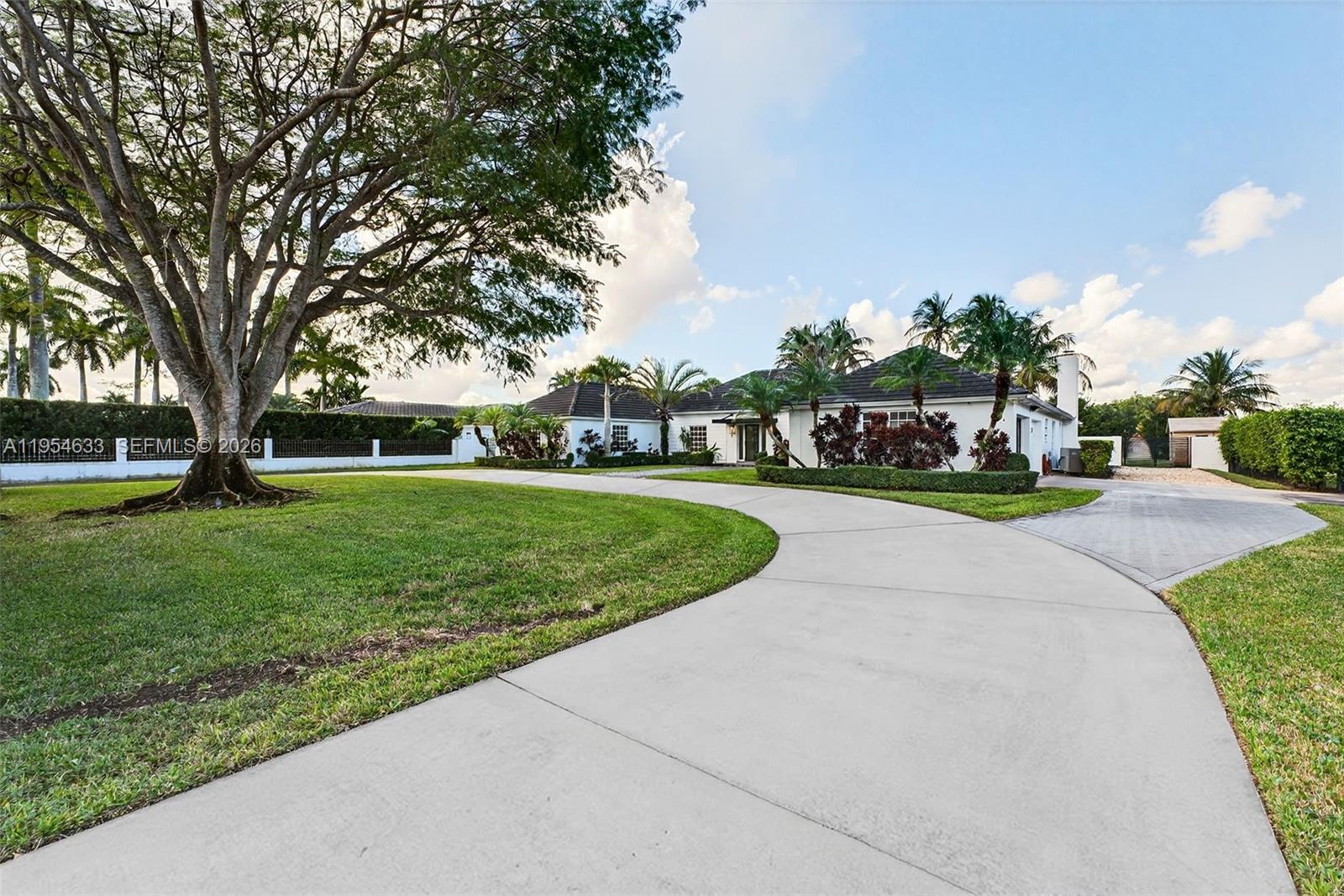 A curved concrete driveway leads to a single-story house with a large tree — 3000 SW 130th Ave, Miami FL 33175, MIAMI, FL