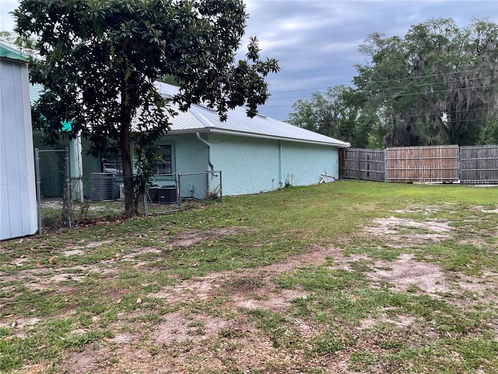 The exterior of a light green house with a metal roof and a fenced yard — 360 S LAKEVIEW DRIVE, LAKE HELEN, FL