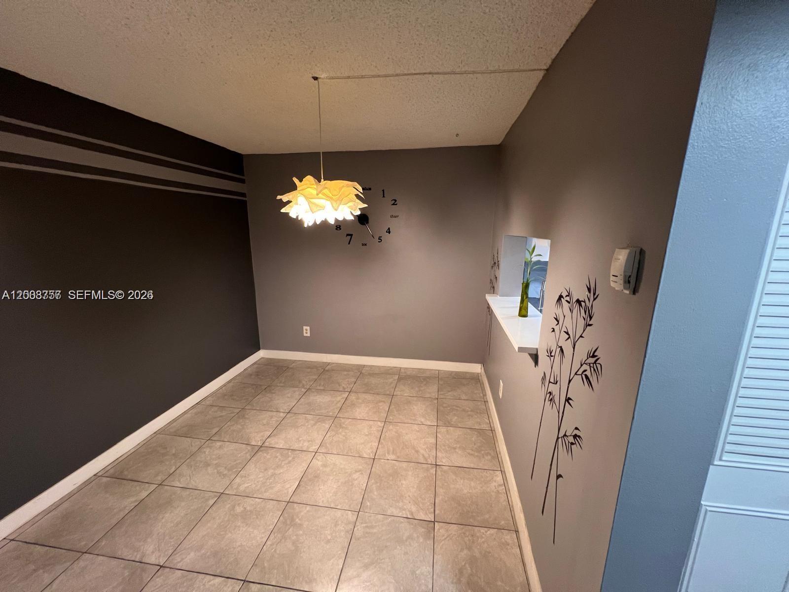 A dining area features gray walls, tile flooring, a modern pendant light, and wall decals — 488 NW 165th St Rd # 610, Miami FL 33169, MIAMI, FL