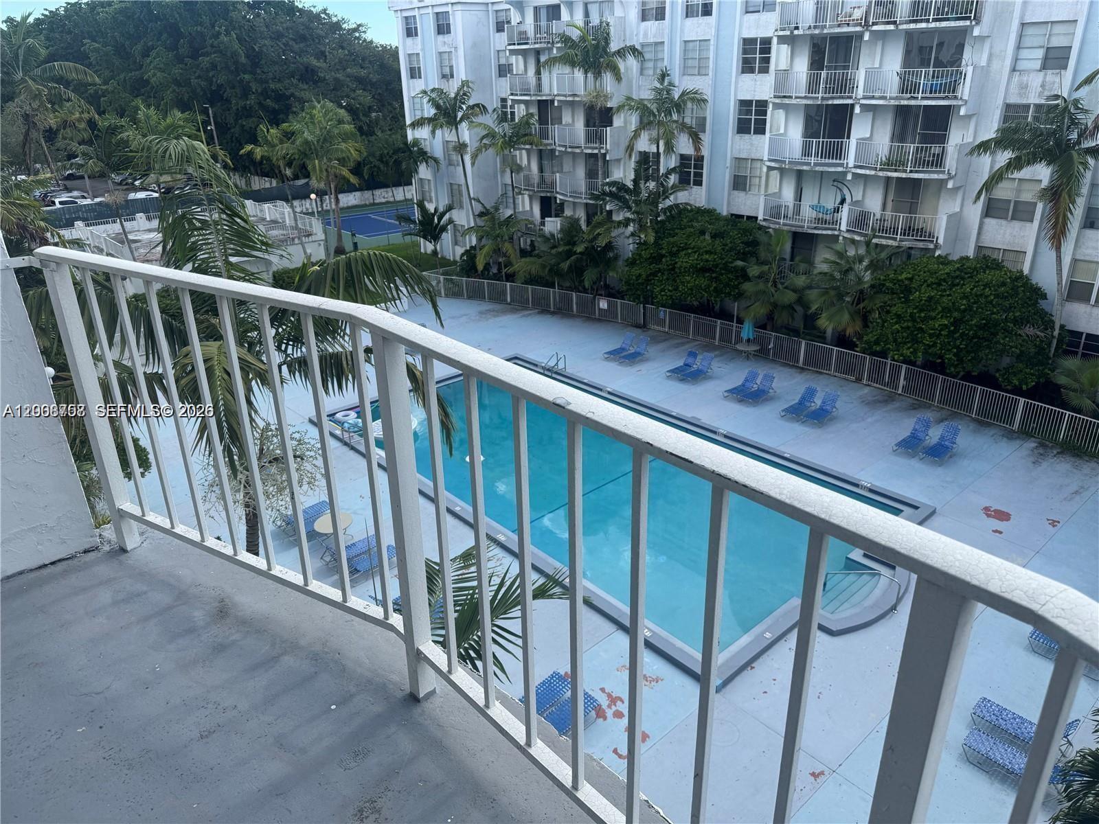 A high-angle view from a balcony overlooking a swimming pool and apartment building — 488 NW 165th St Rd # 610, Miami FL 33169, MIAMI, FL