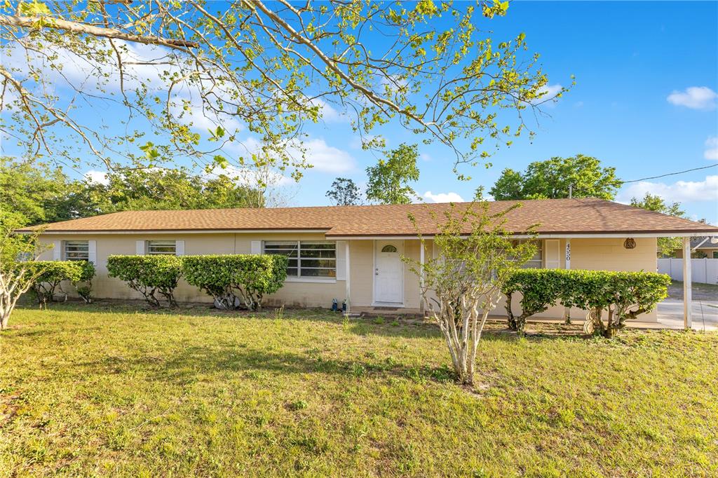 A single-story house with a tan exterior, brown shingled roof, and a front yard — 4550 CHANDLER ROAD, APOPKA, FL