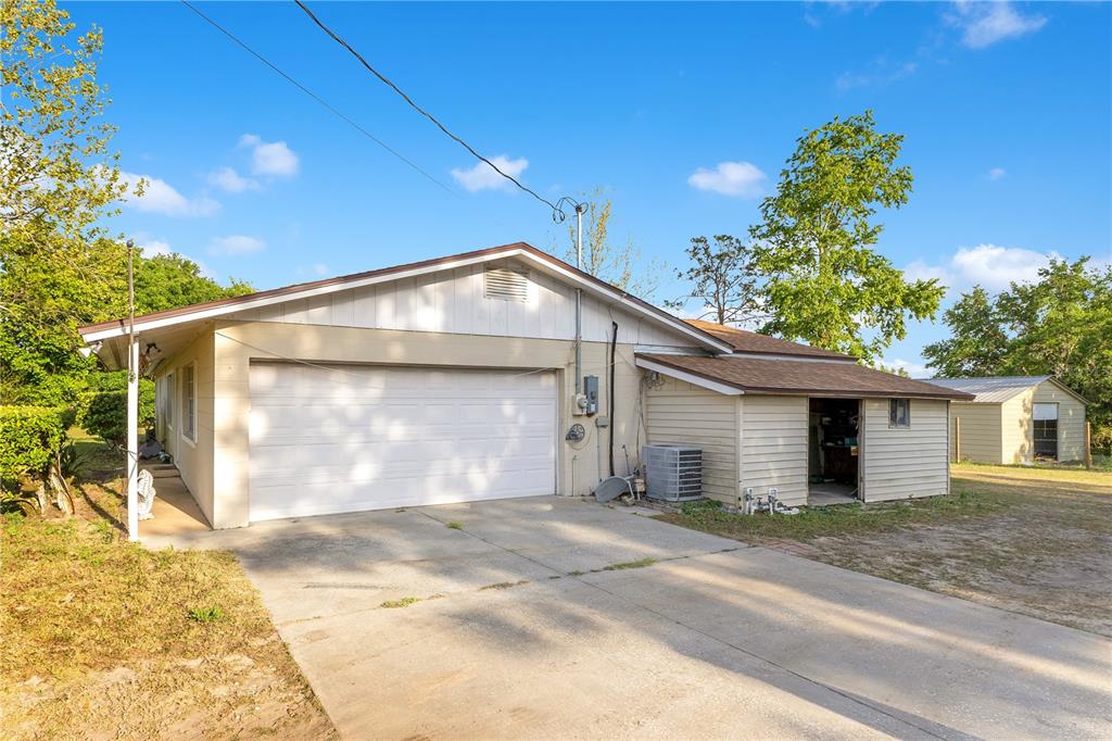 A detached garage with a white door and an attached side shed sits on a concrete driveway — 4550 CHANDLER ROAD, APOPKA, FL