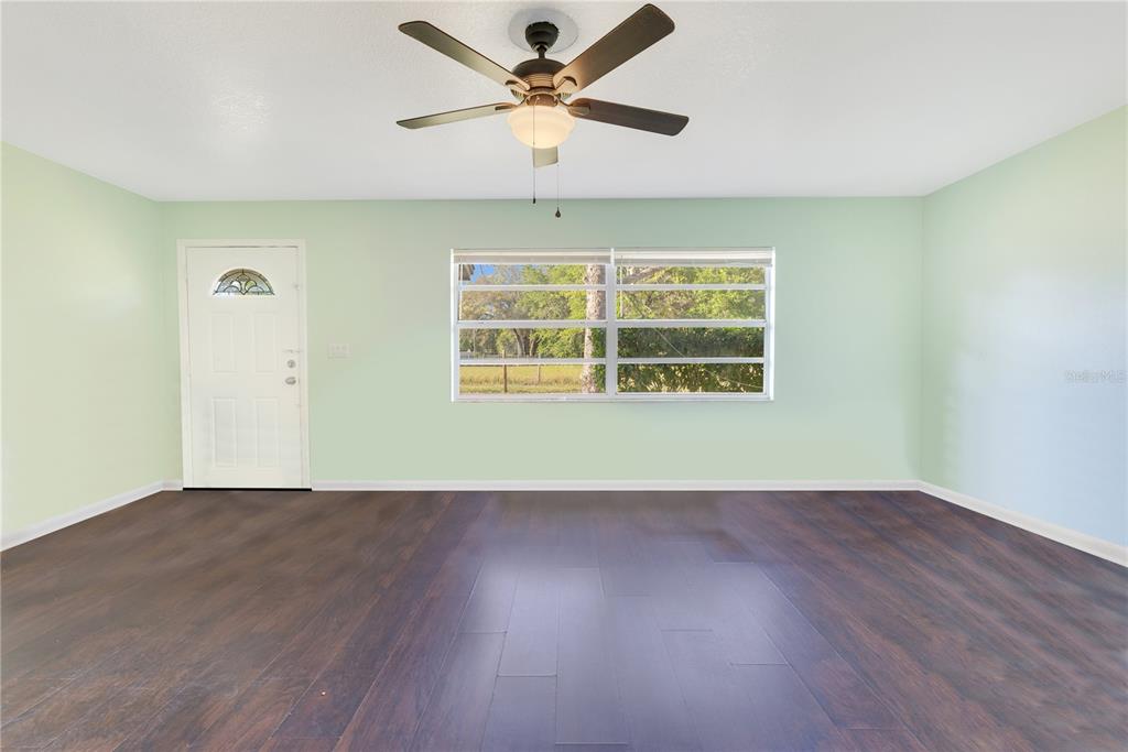 An empty room with light green walls, dark wood flooring, a ceiling fan, and a window — 4550 CHANDLER ROAD, APOPKA, FL