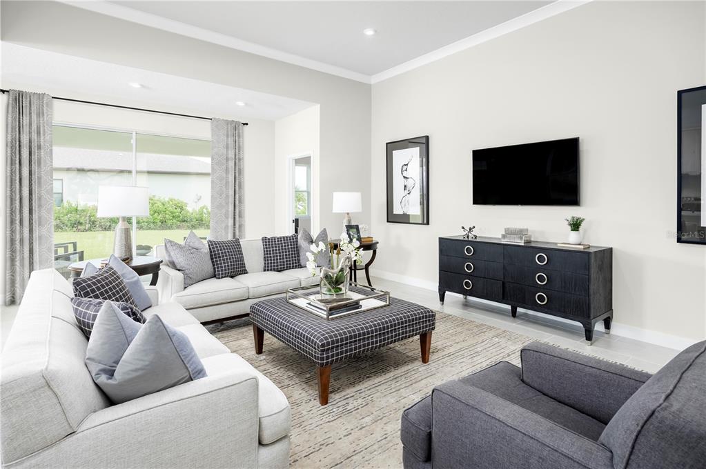 A living room features light gray sofas, a plaid ottoman, and a dark media console — 3255 TIGER PALM WAY, NEW SMYRNA BEACH, FL