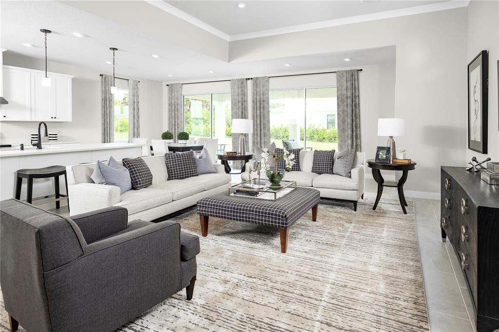 A bright, open-concept living room features neutral furniture, a plaid ottoman, and a modern kitchen — 3255 TIGER PALM WAY, NEW SMYRNA BEACH, FL