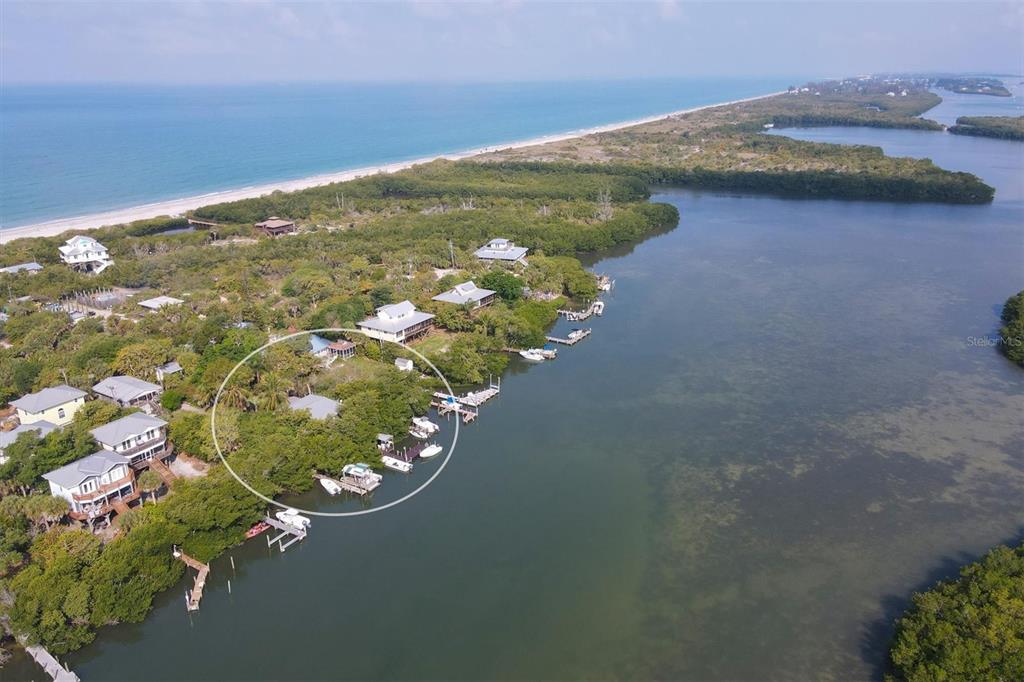 An aerial view shows a waterfront house surrounded by trees with several boat docks nearby — 8144 LITTLE GASPARILLA ISLAND, PLACIDA, FL