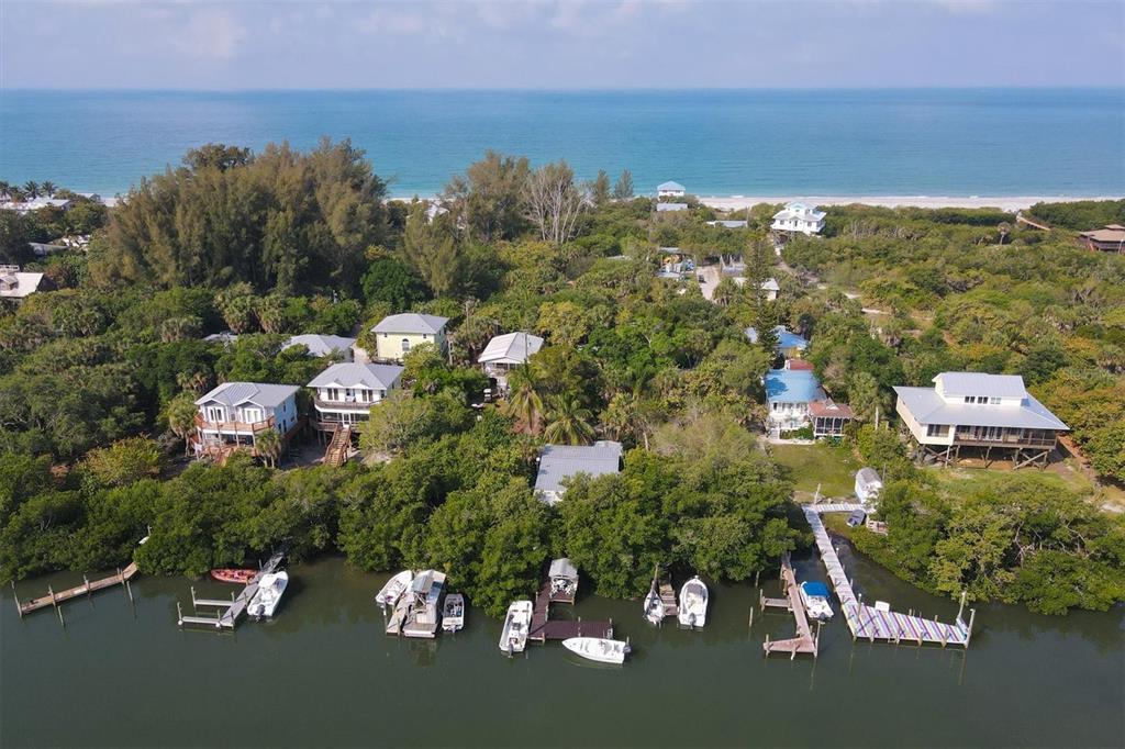 An aerial view of waterfront homes surrounded by dense trees near a sandy beach — 8144 LITTLE GASPARILLA ISLAND, PLACIDA, FL