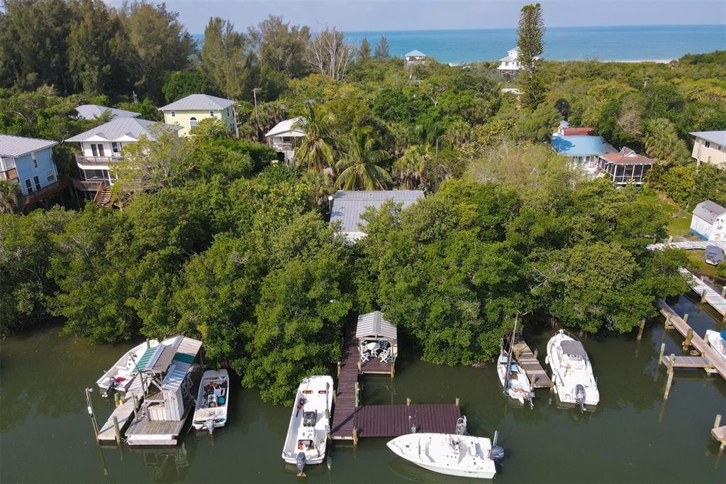 An aerial view shows several houses nestled in dense trees along a canal with boats — 8144 LITTLE GASPARILLA ISLAND, PLACIDA, FL