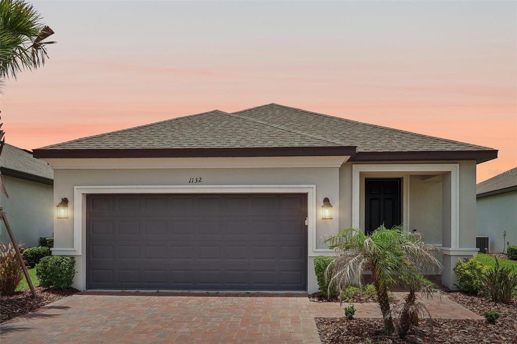 A single-story house exterior features a two-car garage, a covered entryway, and a paved driveway — 1132 VIA GALUPPI STREET, KISSIMMEE, FL
