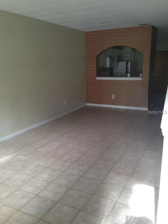 An open living area features light-colored tile flooring and a kitchen pass-through with an archway — 4214 PLANTATION COVE DRIVE, ORLANDO, FL