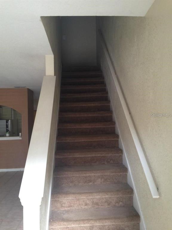 A carpeted staircase leads upward between a white railing and a beige wall — 4214 PLANTATION COVE DRIVE, ORLANDO, FL