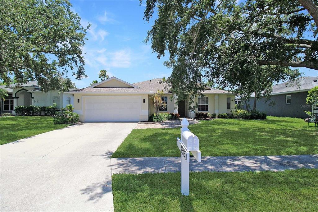 A single-story house with a two-car garage, a concrete driveway, and a large front tree — 4815 77TH STREET E, BRADENTON, FL