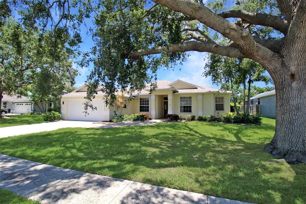 A single-story house with a two-car garage and a large oak tree in the yard — 4815 77TH STREET E, BRADENTON, FL