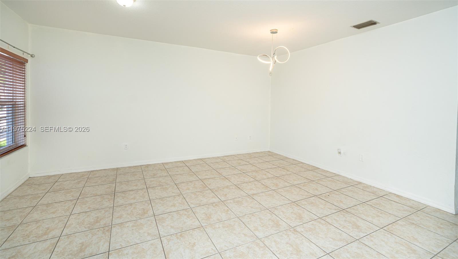 An empty room features white walls, light-colored tile flooring, and a modern circular light fixture — 14046 SW 49th St # 16, Miramar FL 33027, MIRAMAR, FL