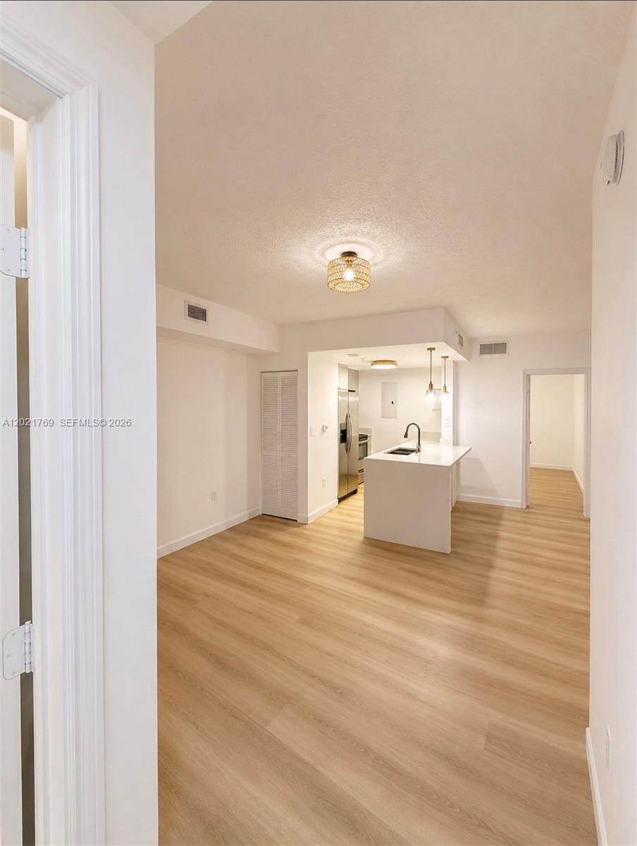 An open-concept kitchen with a white island and light wood-look flooring — 275 NE 18th St # 910, Miami FL 33132, MIAMI, FL
