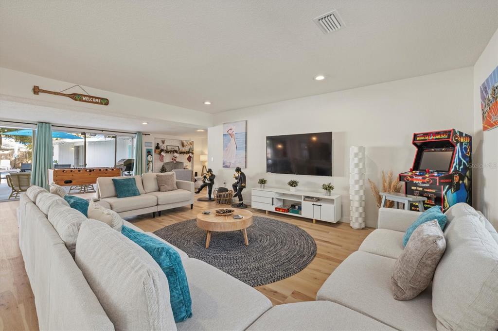 A living room features light wood floors, a large sectional, a television, and an arcade game — 2069 BOUGAINVILLEA STREET, SARASOTA, FL