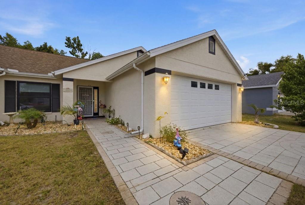 A single-story house features a white stucco exterior, a two-car garage, and a paved walkway — 10249 RAINBOW OAKS DRIVE, HUDSON, FL