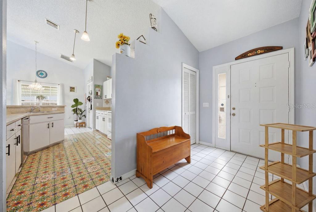 An entryway with white tile floors leads to a kitchen featuring patterned tile flooring — 10249 RAINBOW OAKS DRIVE, HUDSON, FL