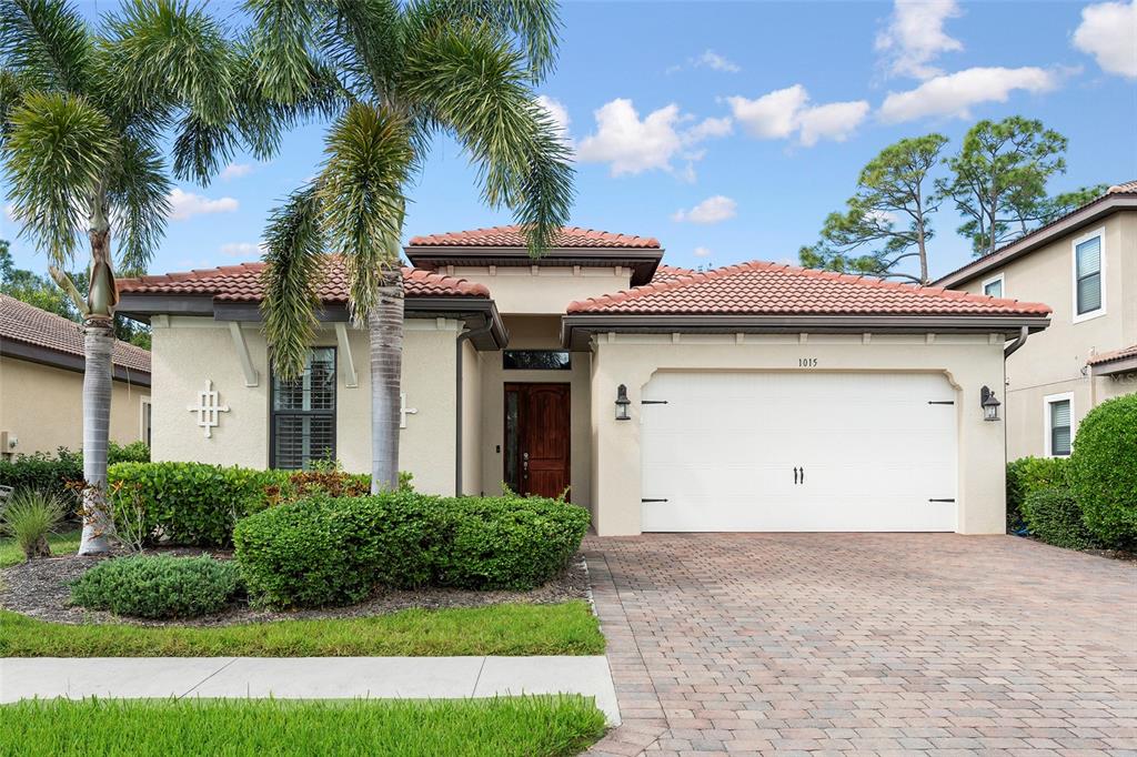 A single-story house with a tiled roof, a two-car garage, and a palm tree — 1015 BLUFFWOOD DRIVE, NOKOMIS, FL
