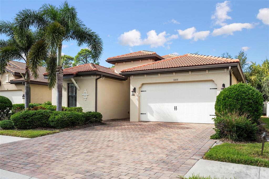 A single-story house with a white garage, tile roof, and a brick paver driveway — 1015 BLUFFWOOD DRIVE, NOKOMIS, FL