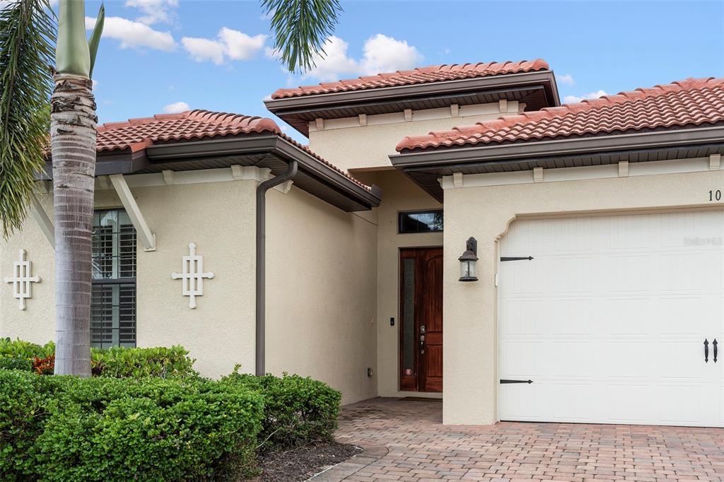 The exterior of a house features a tiled roof, a garage, and a front entrance — 1015 BLUFFWOOD DRIVE, NOKOMIS, FL