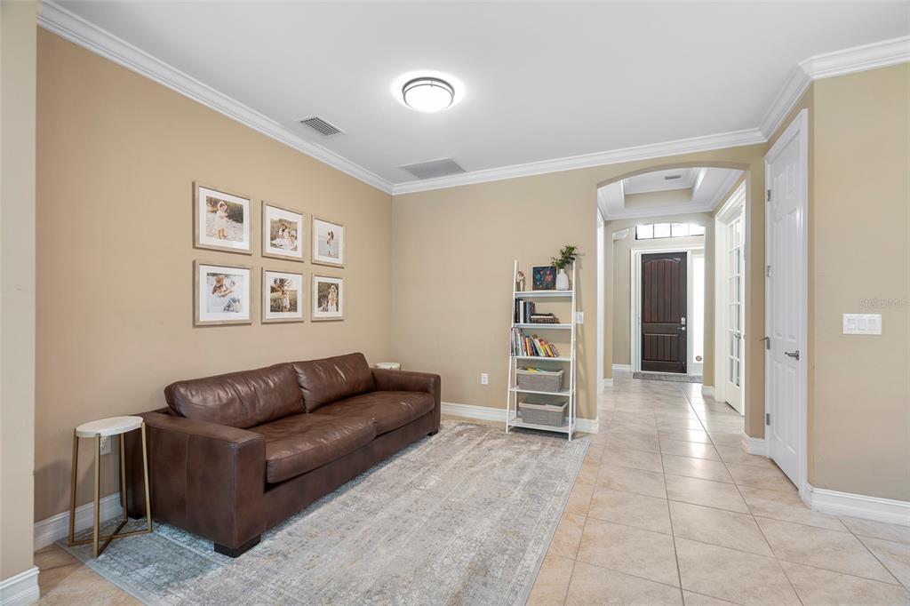 A living room features a brown leather sofa, a white bookshelf, and a framed gallery wall — 1015 BLUFFWOOD DRIVE, NOKOMIS, FL