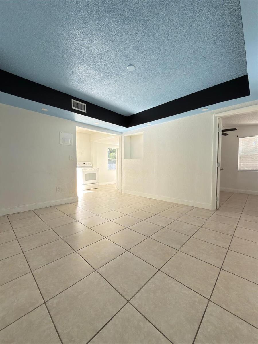 A room with light-colored tile flooring, white walls, and a blue tray ceiling with black trim — 1832 NE 49th Street, Pompano Beach FL 33064, POMPANO BEACH, FL