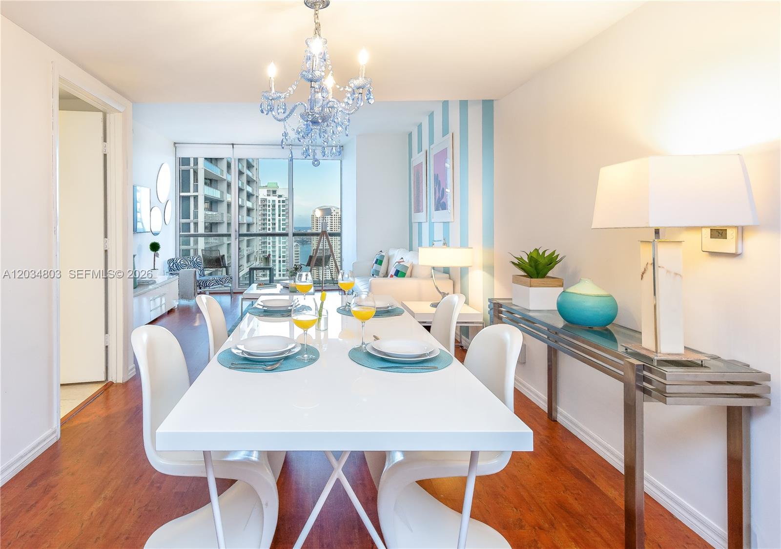 A dining room features a white table, modern chairs, a blue chandelier, and striped wallpaper — 485 Brickell Ave # 3211, Miami FL 33131, MIAMI, FL