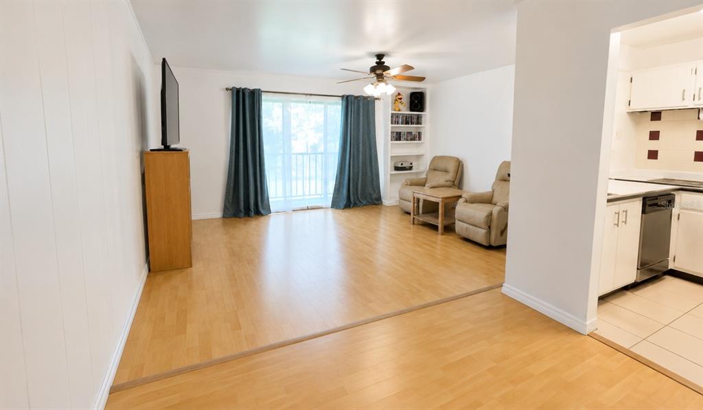 A living room with light wood flooring, a ceiling fan, and a sliding glass door — 1500 VIRGINIA AVENUE UNIT 209, DAYTONA BEACH, FL