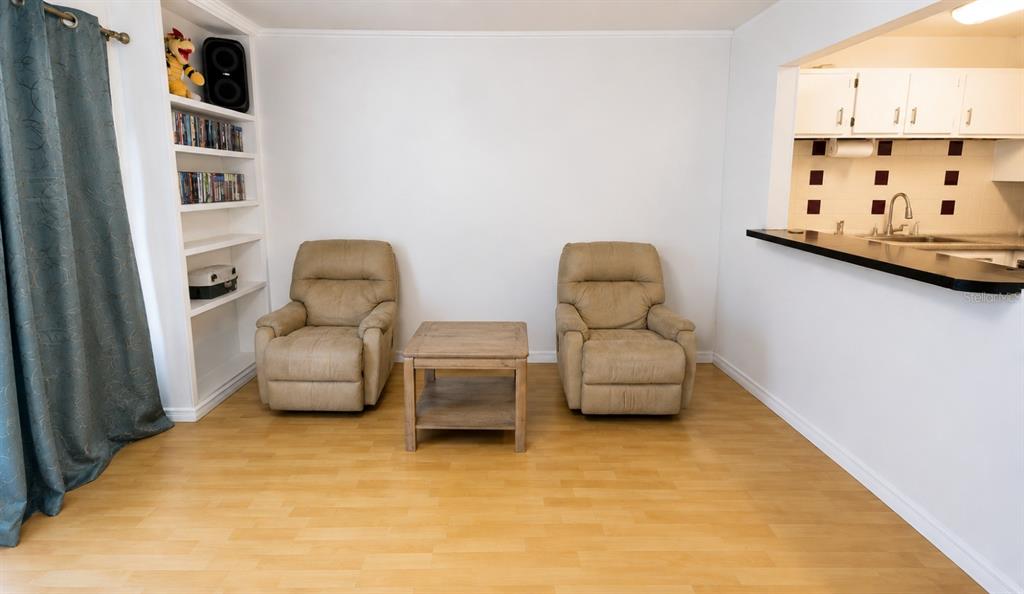 A living room features two tan recliners, a wooden side table, and built-in shelving — 1500 VIRGINIA AVENUE UNIT 209, DAYTONA BEACH, FL