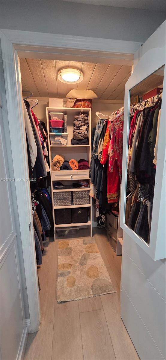 A walk-in closet features white shelving, hanging clothes, and a light-colored wood floor — NORTH LAUDERDALE, FL