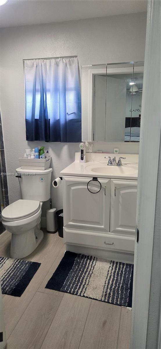 A bathroom features a white vanity, a toilet, a medicine cabinet, and blue-toned curtains — NORTH LAUDERDALE, FL