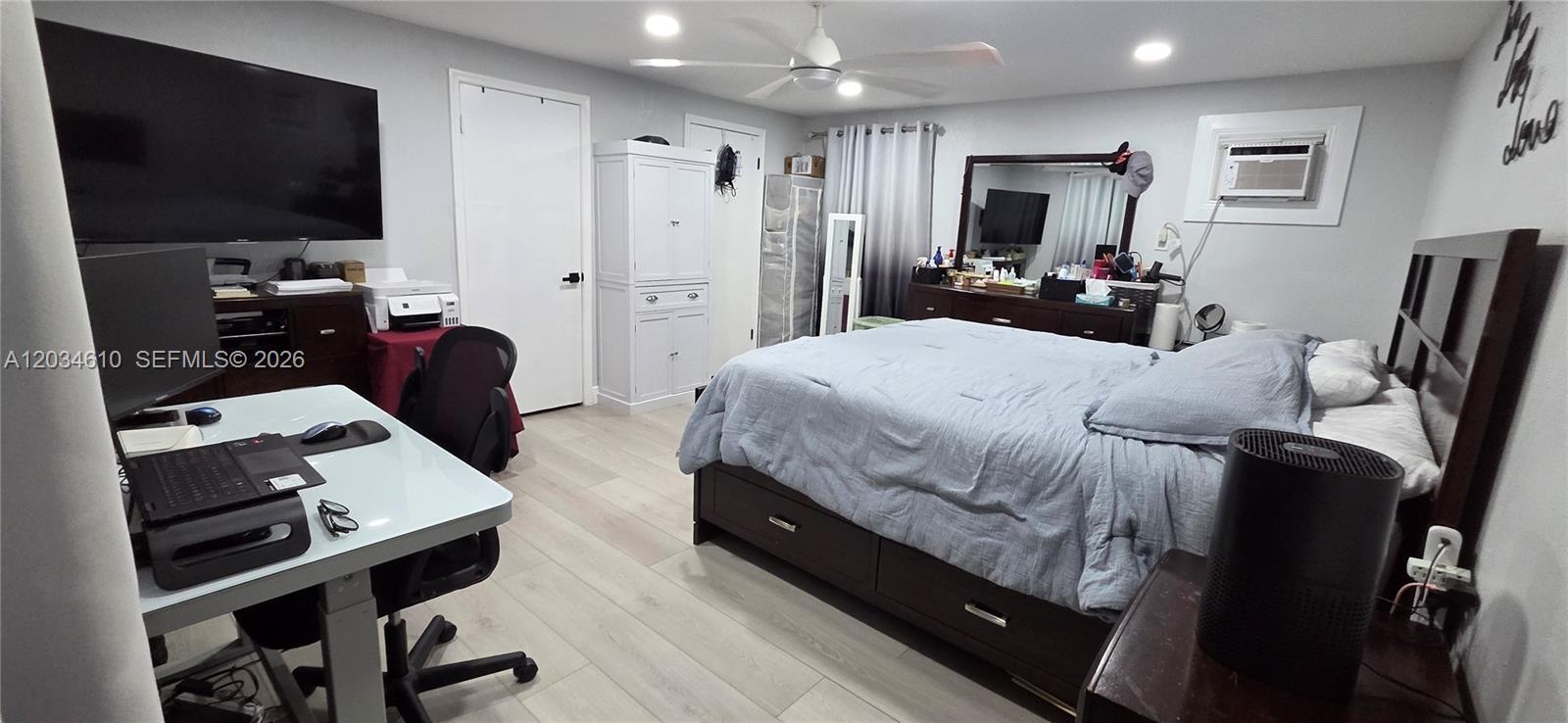 A bedroom features a bed, a desk, a television, and light-colored wood-look flooring — NORTH LAUDERDALE, FL