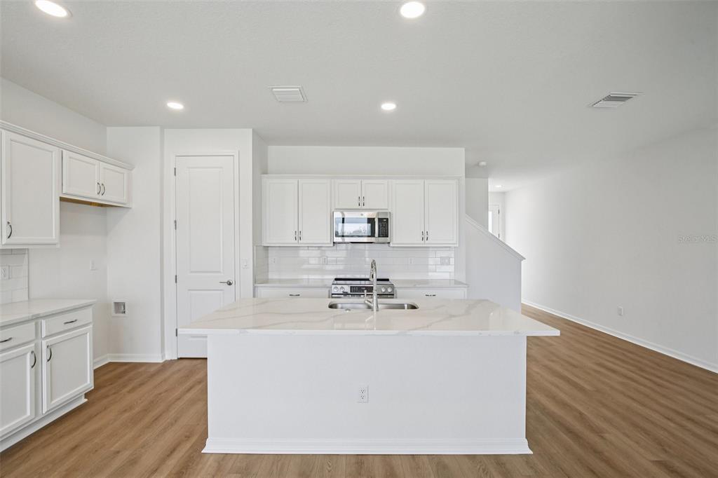 A bright kitchen and dining area with white cabinets, a central island, and wood flooring — 31481 SPANISH MISSION ROAD, SAN ANTONIO, FL
