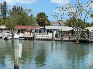 A view of waterfront houses with private docks along a canal under a blue sky — 249 BOCA CIEGA DRIVE, MADEIRA BEACH, FL