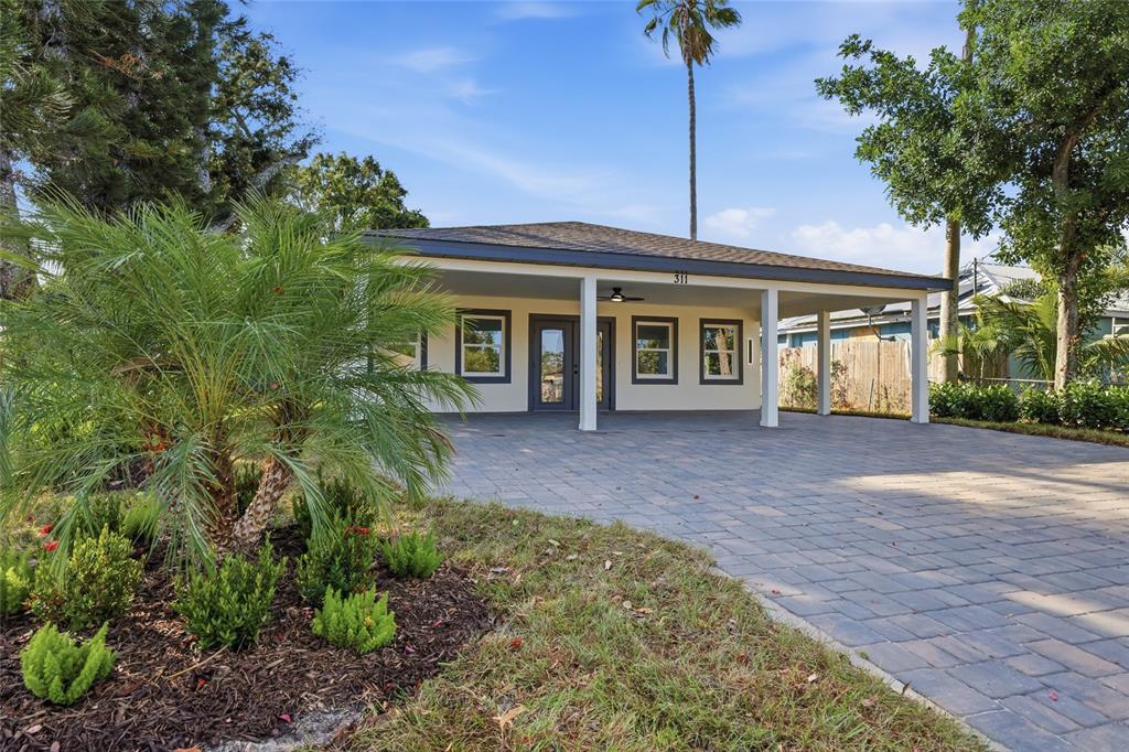 A single-story house with a paved driveway, a covered carport, and a palm tree — 311 12TH STREET W, PALMETTO, FL